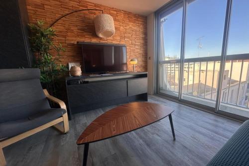 - un salon avec une télévision, une chaise et une table dans l'établissement LES PIEDS DANS L'EAU - Magnifique P2 proche de la mer, au Grau-du-Roi