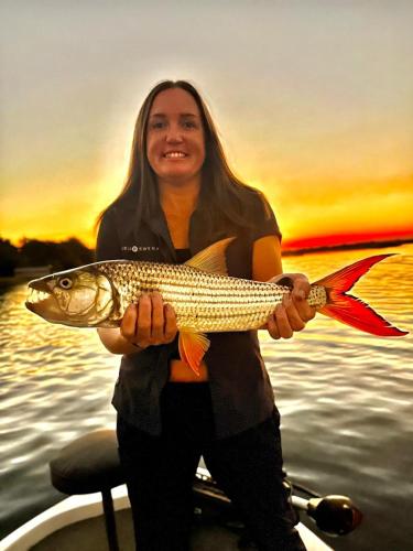 a woman holding a fish in her hands on a boat at Kubu & Kwena Lodge in Katima Mulilo