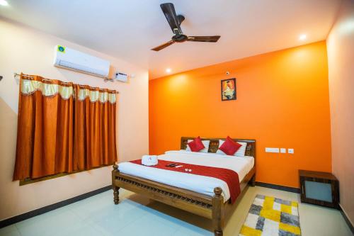 a bedroom with a bed with an orange wall at Sri Balaji Villas Pondicherry with Car Parking in Pondicherry