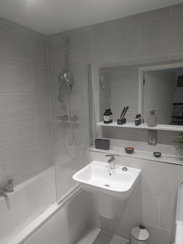 a white bathroom with a sink and a shower at Stylish Harbourside Apartment in Bristol