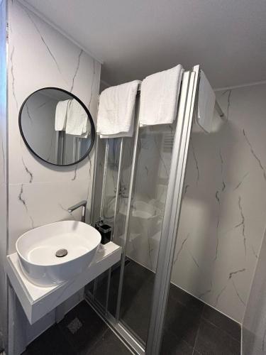 a white bathroom with a sink and a mirror at Hotel Bucovina in Suceava