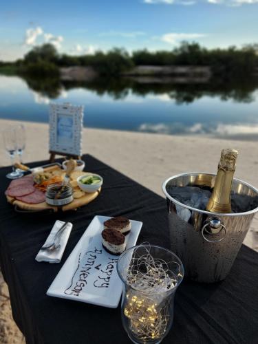 a table with a bottle of champagne and food on the beach at Kubu & Kwena Lodge in Katima Mulilo