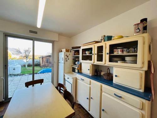 une cuisine avec une table et un réfrigérateur dans l'établissement Maison ALIS 5 pièces 10 personnes à 100 mètres de la plage du Courégant, à Ploemeur
