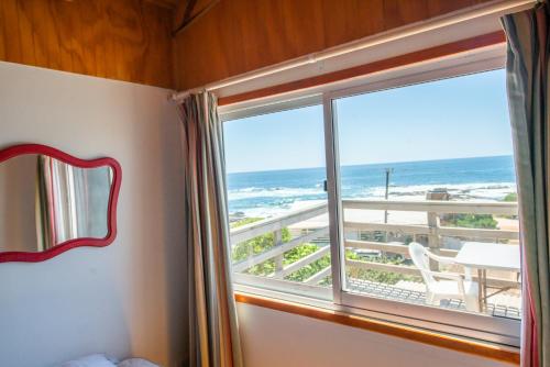 a bedroom with a window with a view of the ocean at Cabaña Ideal in Valparaíso