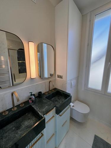 une salle de bain avec un lavabo, des toilettes et un miroir dans l'établissement Superbe appartement Art Déco avec roof top, à Cannes