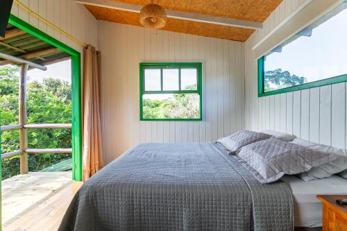 a bedroom with a bed and two windows at Sua casa na Guarda com jardim privado in Guarda do Embaú