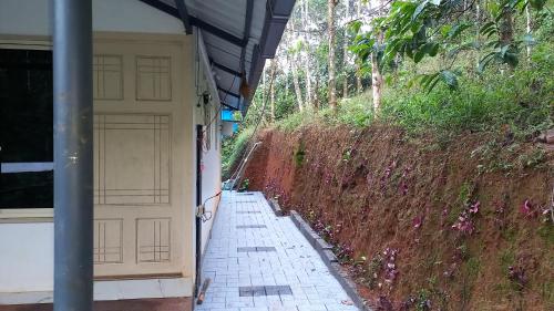 a building with a garage door and a brick sidewalk at Pepper Mist Wayanad Homestay in Tindummal