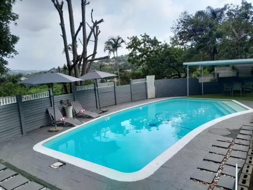 a swimming pool with chairs and an umbrella at 54 Malcolm Hidden Gem near Musgrave in Durban