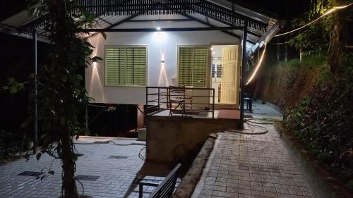 a house with green shutters and a porch at night at Pepper Mist Wayanad Homestay in Tindummal