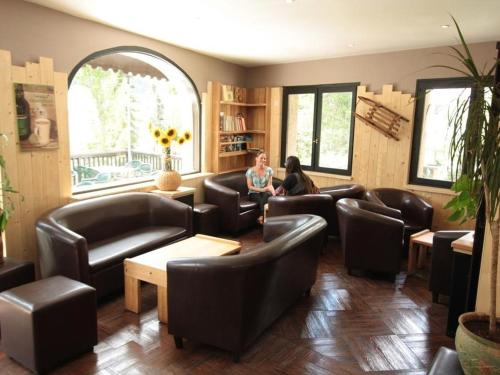 a woman sitting in a waiting room with leather chairs at Hôtel les Vallois in Vallouise