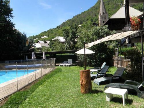 a pool with chairs and an umbrella next to a fence at Hôtel les Vallois in Vallouise