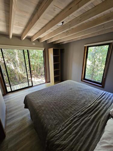 a bedroom with a large bed and two windows at Inspiramide Pucon in Pucón