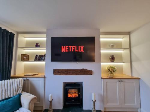 ein Wohnzimmer mit einem Fernseher über einem Kamin in der Unterkunft Stunning Cottage in Knutsford by City SuperHost in Knutsford