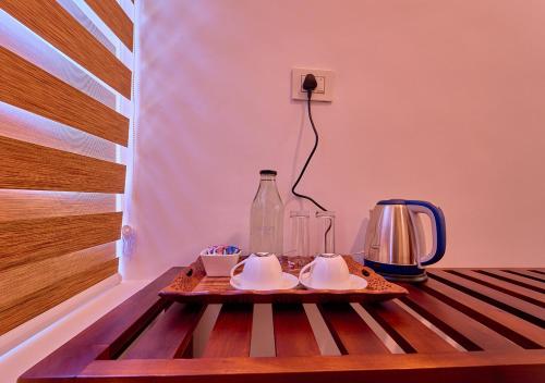 a tray with cups and a bottle on a table at VOYE HOMES Signature Pool Resort Varkala , Just 950 m from Varkala Cliff and Beach in Varkala