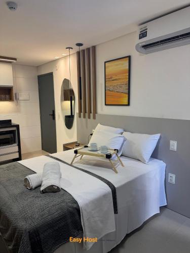 a bedroom with a large white bed with a table on it at Flats Tramonto - By EasyHost in João Pessoa