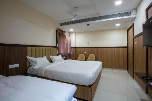 a hotel room with two beds and a television at Hotel PRM Aruna Archadia in Erode