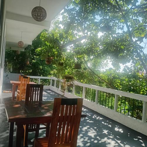 a table and chairs on a porch with trees at Daasa Guest Mirissa in Mirissa
