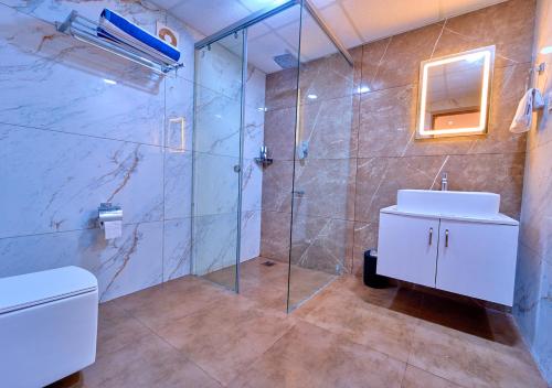 a bathroom with a shower and a toilet and a sink at VOYE HOMES Signature Pool Resort Varkala , Just 950 m from Varkala Cliff and Beach in Varkala