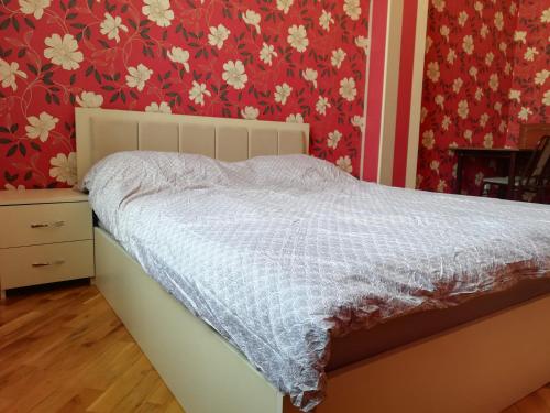 un letto in una camera da letto con carta da parati rossa e bianca di Private Room in Shared Apartment a Baku
