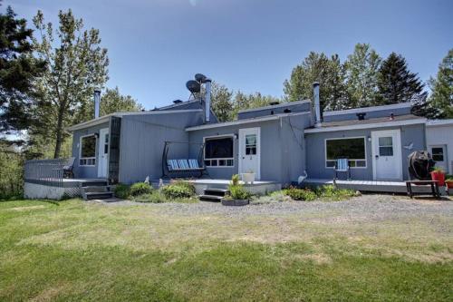 a gray house with a yard in front of it at Oasis du grand fond Inc in La Malbaie