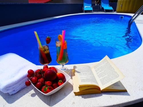 un libro y un bol de fruta junto a la piscina en Apartment in Croatia by the Seafront, en Dramalj
