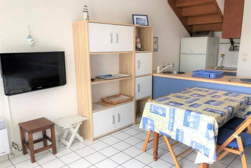 Cette chambre comprend une cuisine avec une table et une télévision. dans l'établissement Appartement avec terrasse à 100m plage St-Guirec à PLOUMANAC'H - Réf 896, à Perros-Guirec