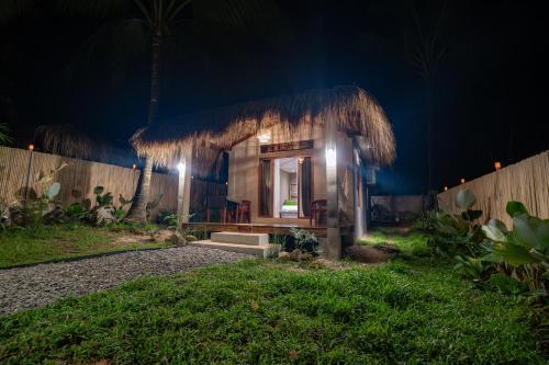 a small house with a straw roof at night at Inigtan Lio Villas in El Nido