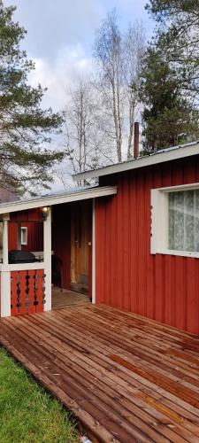 a red house with a wooden deck in front of it at Omakotitalo Haapavesi Mieluskylä in Ollilanperä