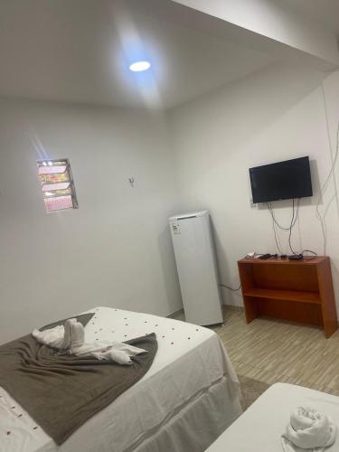 a room with a bed and a television and a table at Villa Brilho do Sol Jeri in Jericoacoara