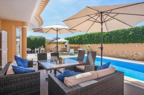 a patio with a table and chairs and an umbrella at Canto do Sol, 4 Bedroom Villa in Lagos