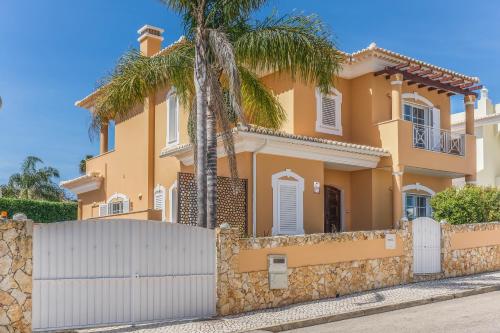 a yellow house with a fence and a palm tree at Canto do Sol, 4 Bedroom Villa in Lagos