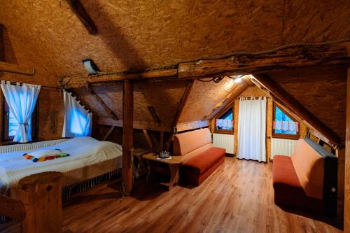 a bedroom with a bed and two chairs in a attic at Pensiunea Doina in Vadu Izei