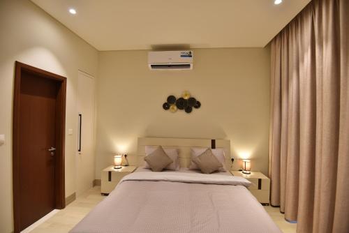 a bedroom with a large bed with two tables and two lamps at Tulip Star Hawana in Salalah