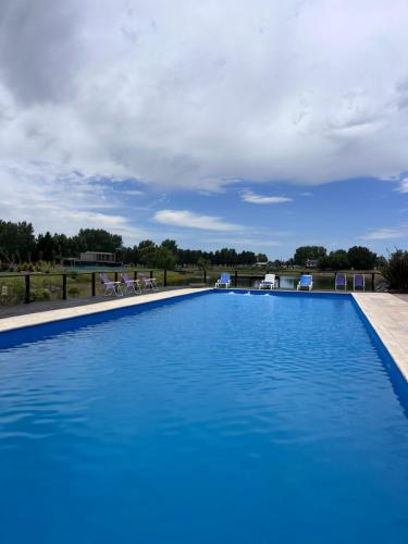 a large swimming pool with blue water and chairs at La casa del lago in Chascomús