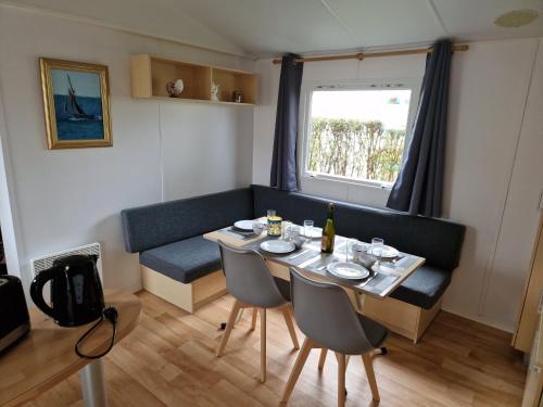 un salon avec une table et un canapé dans l'établissement Mobil Home Beg Meil 300m plage avec piscine partagée, terrasse privée et Wi-Fi, à Fouesnant