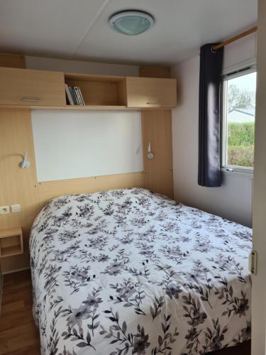 une chambre avec un lit avec un couvre-lit fleuri dans l'établissement Mobil Home Beg Meil 300m plage avec piscine partagée, terrasse privée et Wi-Fi, à Fouesnant