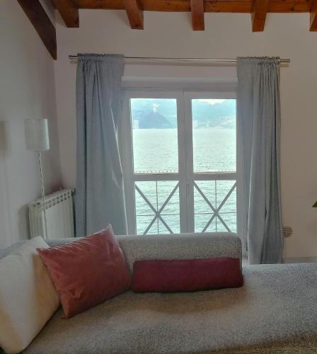 a couch sitting in front of a large window at FilandaLago Apartment in Iseo