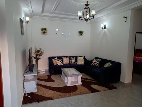 a living room with a black couch and a table at Olympus House Meublé in Yaoundé