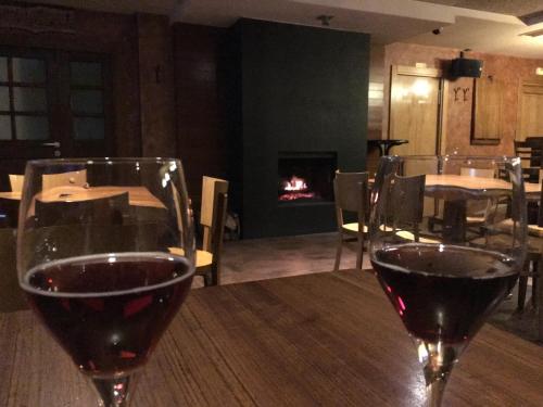 two glasses of wine sitting on a table with a fireplace at Hostal Rural Haizea in Espinal-Auzperri