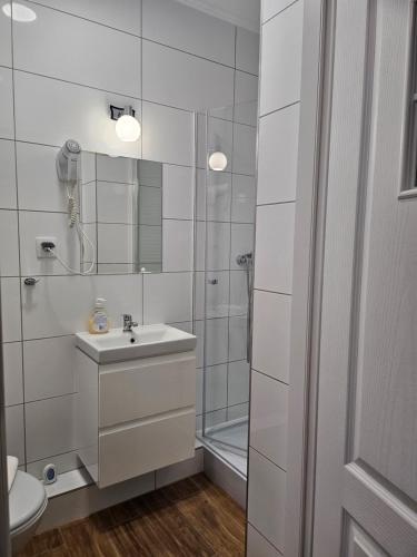 a white bathroom with a sink and a shower at "Hel" Wieniec Zdrój in Włocławek
