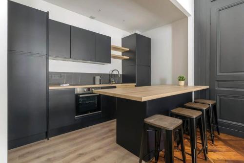 une cuisine avec des placards noirs et un comptoir avec des tabourets dans l'établissement Le Méritant Jacobins Center of Lyon, à Lyon