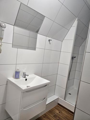 a white bathroom with a sink and a shower at "Hel" Wieniec Zdrój in Włocławek