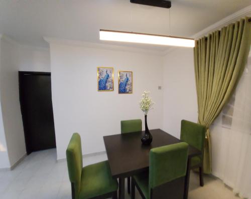 a dining room with a table and green chairs at Home 11 in Lekki
