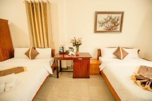 a room with two beds and a table with flowers at Lê Mùi Hotel - Apartment in Da Thien