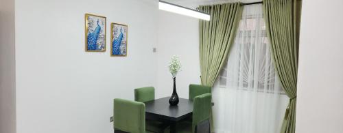 a dining room with a table and green chairs at Home 11 in Lekki