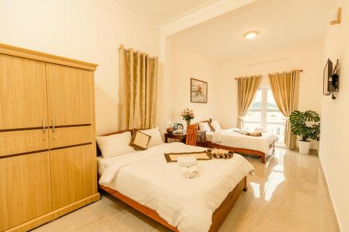 a bedroom with two beds and a large window at Lê Mùi Hotel - Apartment in Da Thien