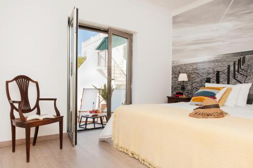 a white bedroom with a bed and a chair at Beachouse - Surf, Bed & Breakfast in Ericeira
