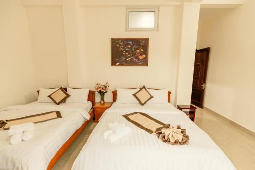 two beds in a room with white walls at Lê Mùi Hotel - Apartment in Da Thien