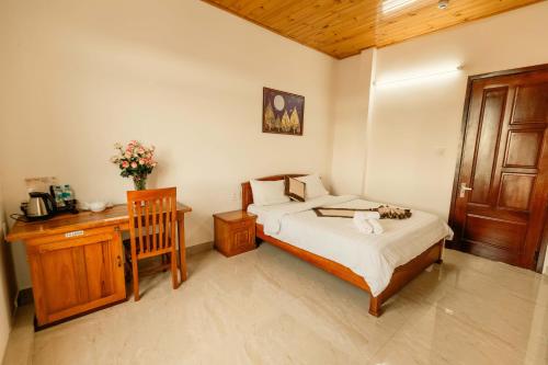 a bedroom with a bed and a table and a desk at Lê Mùi Hotel - Apartment in Da Thien