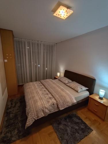 a bedroom with a bed in a room with a window at Apartment Block D in Podgorica